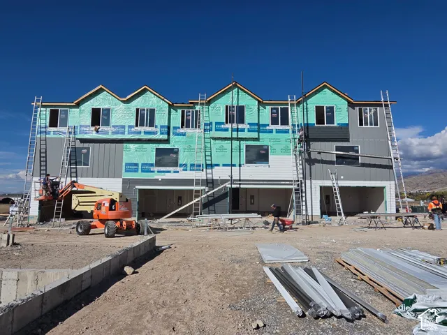 Multi-unit residential structure featuring horizontal and vertical siding, multi-gabled roofline, and integrated multi-car garage bays