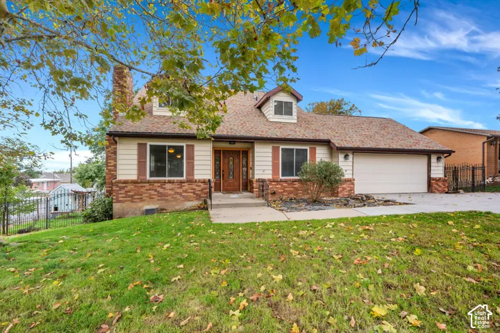 Split-level exterior featuring a brick and horizontal siding facade, shingled roof, two dormer windows, and an attached two-car garage