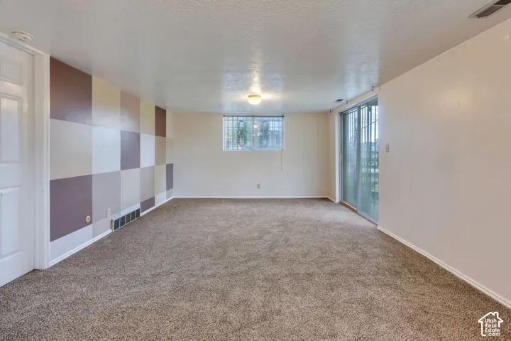 Neutral wall-to-wall carpeting, decorative multi-tone checkered wall paneling, sliding glass door, and large picture window