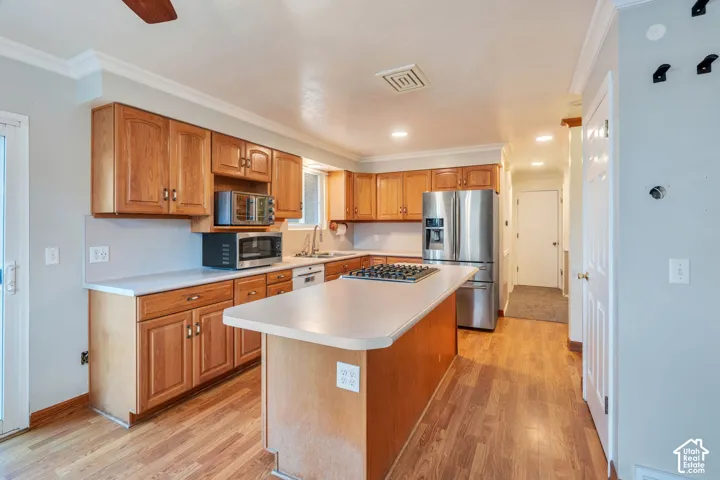 Kitchen featuring wood cabinetry, a central island with a cooktop, solid-surface countertops, and wood-finish flooring