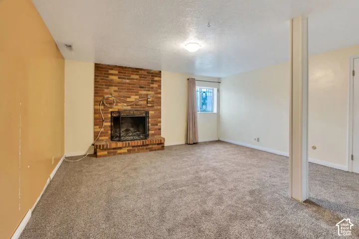 Floor-to-ceiling brick fireplace with a raised brick hearth, neutral wall-to-wall carpeting, and a structural column