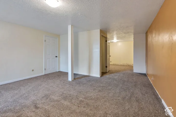 Interior space featuring wall-to-wall carpeting, a structural support column, two interior doors, and overhead flush-mount lighting fixtures