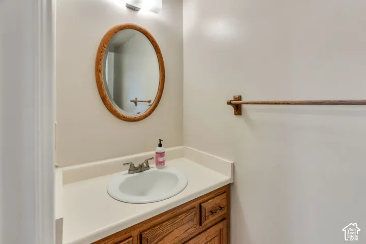 Wood-finish vanity featuring an integrated basin, oval wall-mounted mirror with a wood frame, and matching wooden towel rack