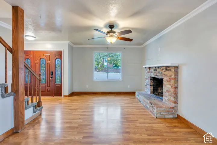 Living area featuring wood-finish flooring, a floor-to-ceiling brick fireplace with a raised hearth, and a stained wood front door with decorative glass inserts