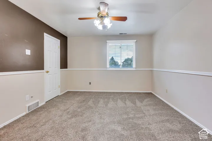 Interior room featuring carpeting, chair rail molding, a multi-light ceiling fan, and a single-pane window with installed blinds