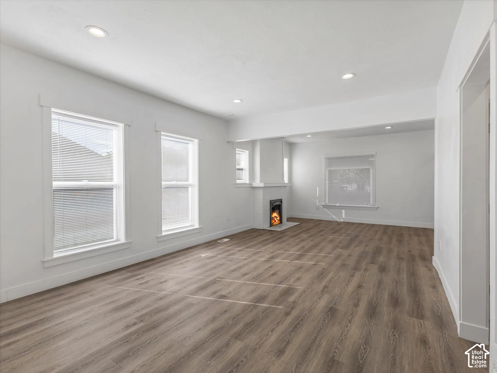 Spacious interior featuring wood-finish flooring, recessed lighting, white walls, and a fireplace with a white mantel