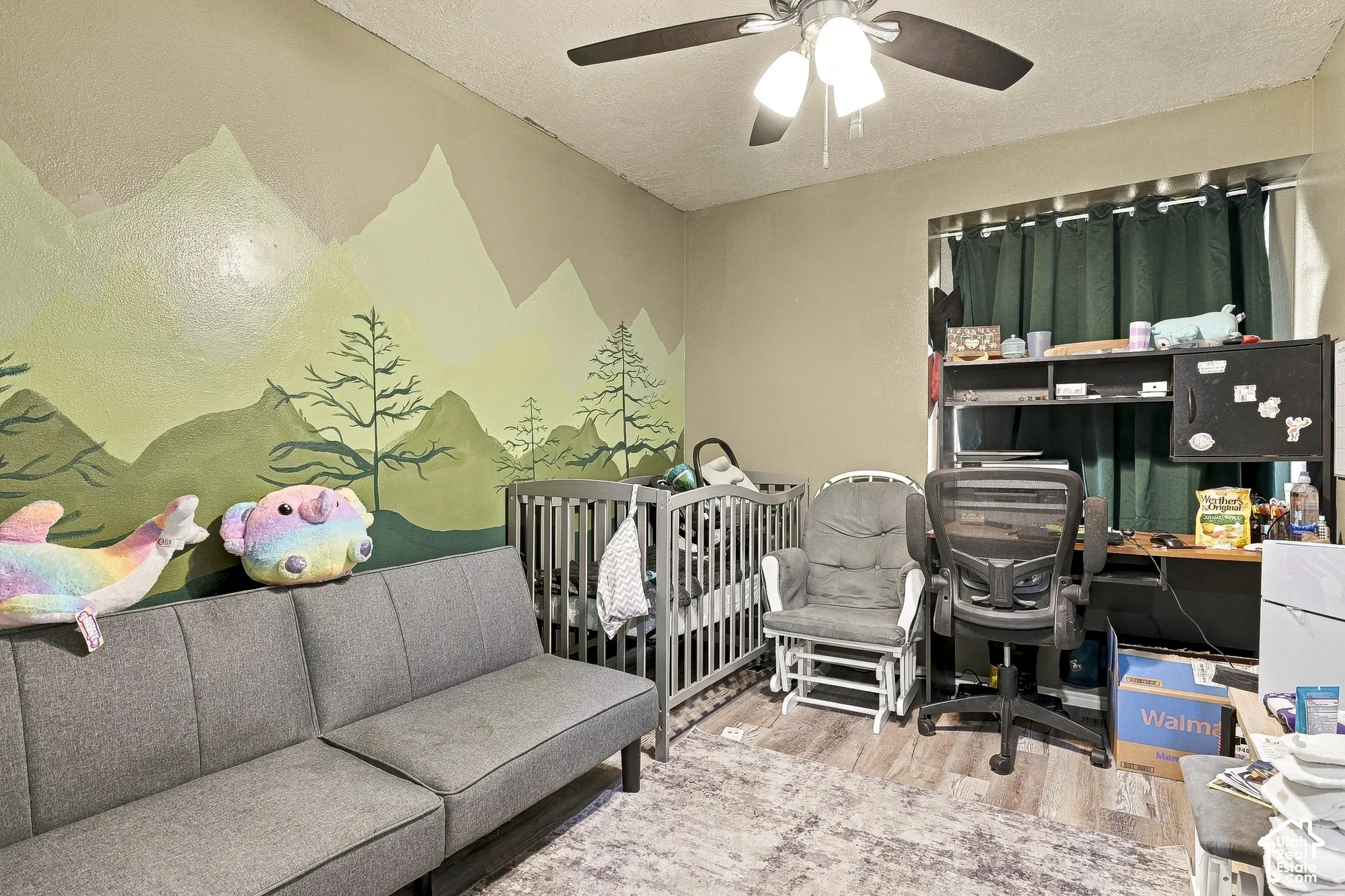 Room featuring wood-finish flooring, a ceiling fan with integrated lighting, and decorative wall mural