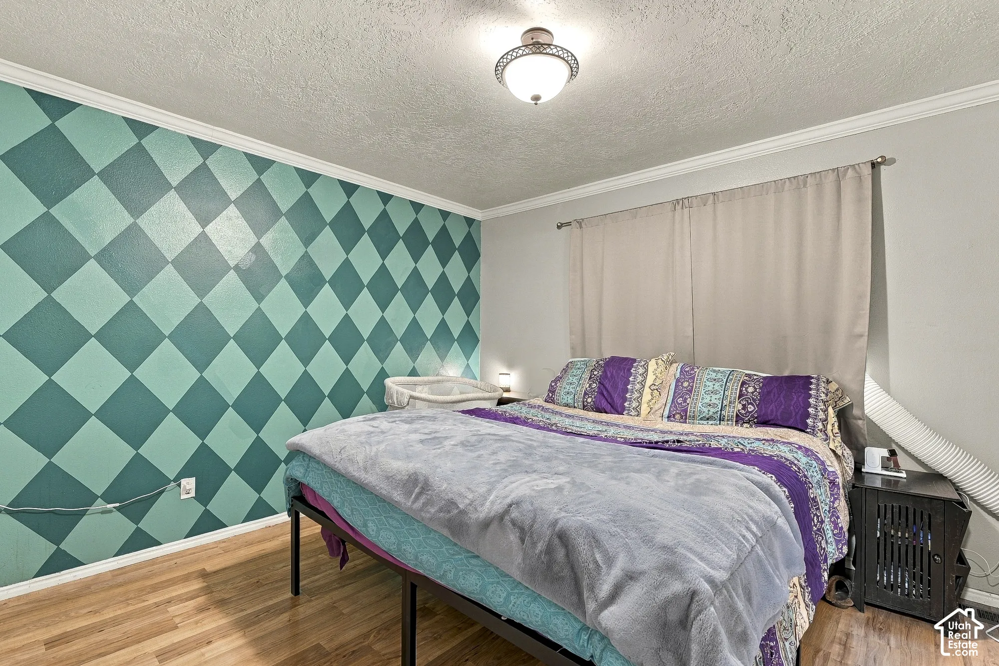 Room featuring wood-finish flooring, a geometric patterned accent wall, and a central flush-mount ceiling light fixture