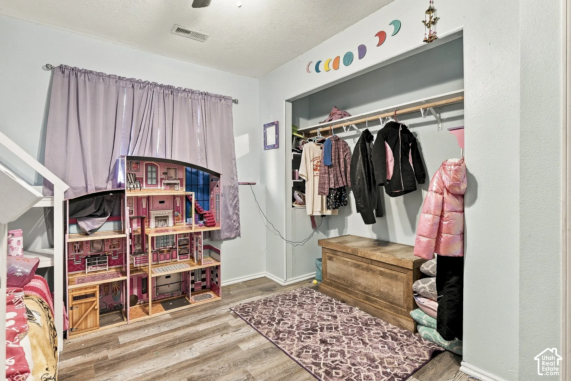 Room featuring wood-finish flooring, an open-concept reach-in closet with overhead shelving, and a ceiling-mounted fan
