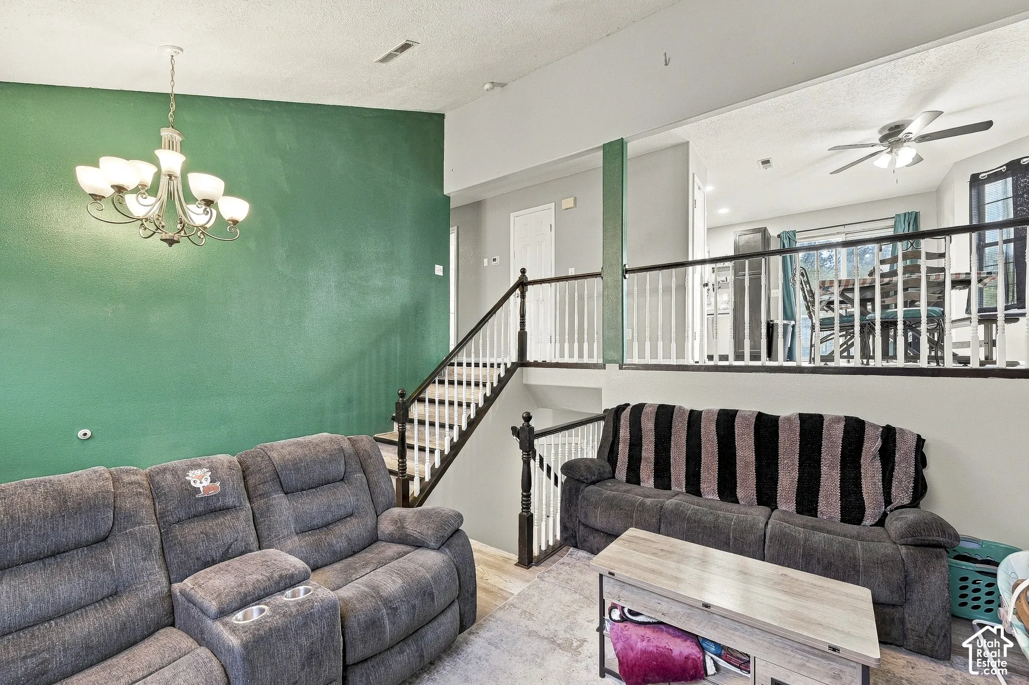Vaulted ceilings, metal chandelier, and staircase featuring a wooden handrail with white balusters