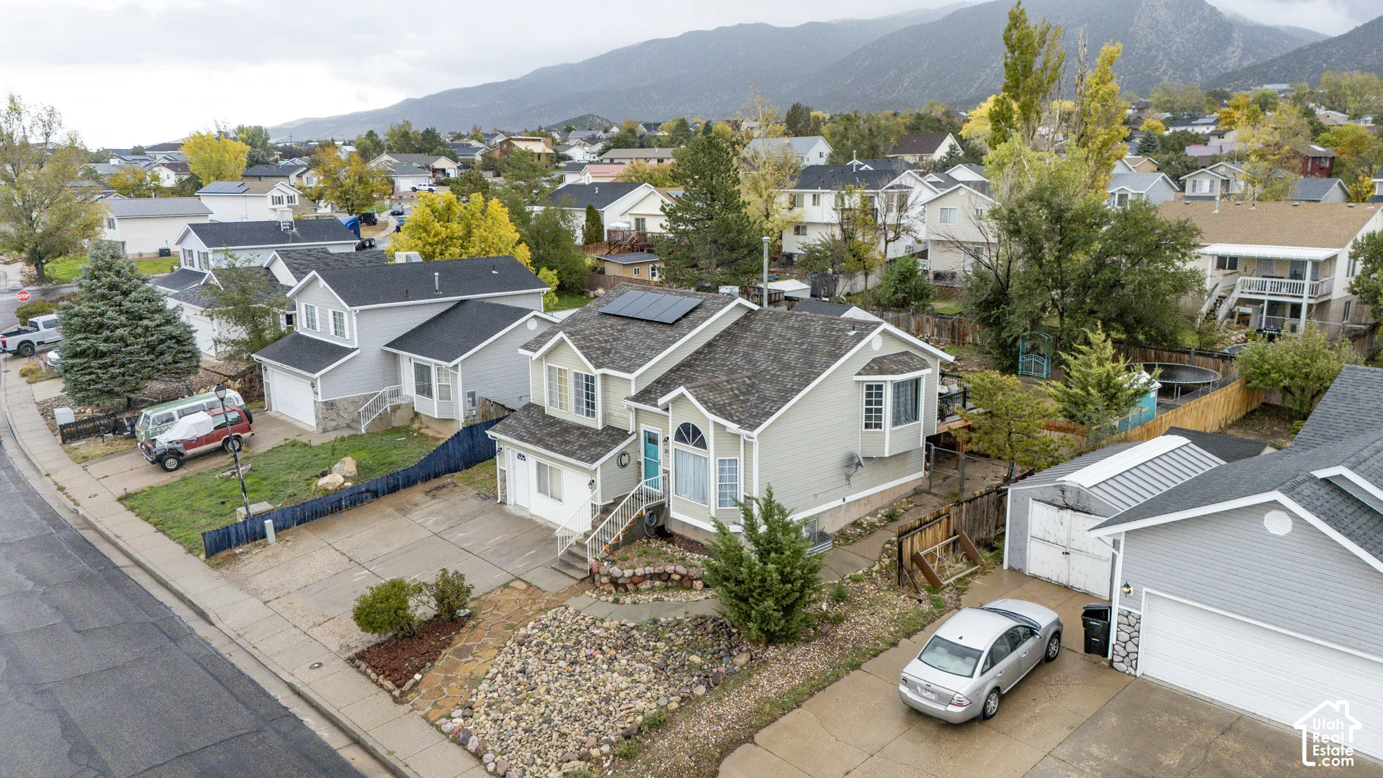 Multi-level residence featuring solar panels, vinyl siding, a bay window, a concrete driveway, and rock landscaping