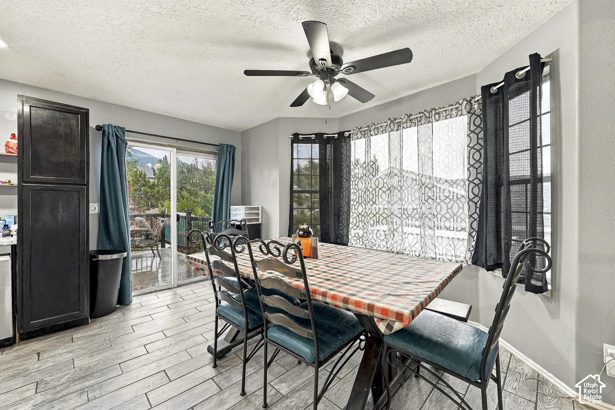 Dining area featuring wood-finish flooring, a multi-pane bay window, sliding glass door, built-in floor-to-ceiling cabinetry, and a ceiling fan with integrated lighting