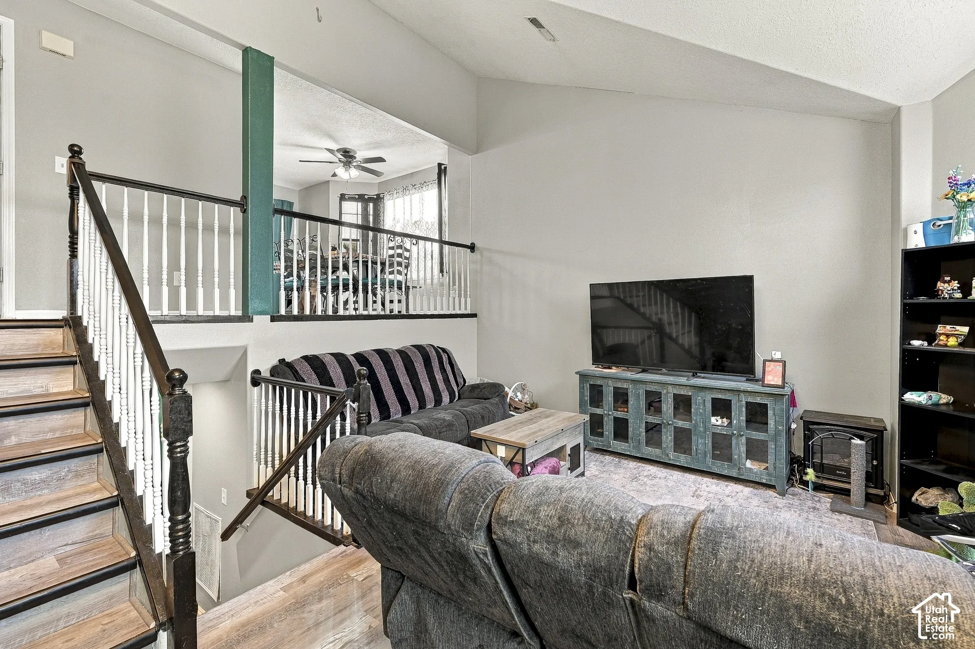 Vaulted ceilings, wood-finish staircase with decorative balusters, and a split-level design featuring a raised landing with a structural post