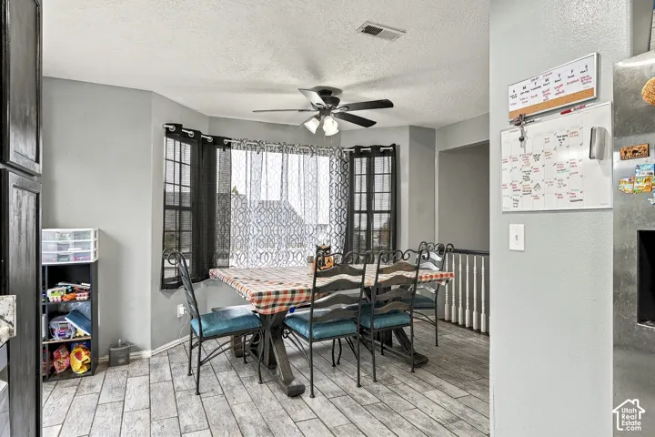 Dining area featuring a bay window, wood-finish tile flooring, and a ceiling-mounted light fixture with a fan