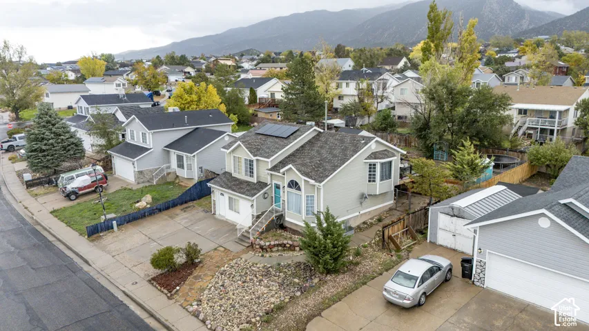 Multi-level residence featuring solar panels, vinyl siding, a bay window, a concrete driveway, and rock landscaping