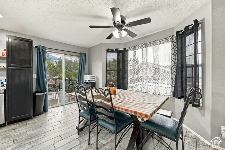 Dining area featuring wood-finish flooring, a multi-pane bay window, sliding glass door, built-in floor-to-ceiling cabinetry, and a ceiling fan with integrated lighting