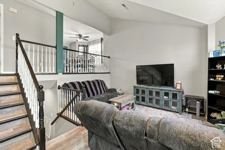 Vaulted ceilings, wood-finish staircase with decorative balusters, and a split-level design featuring a raised landing with a structural post