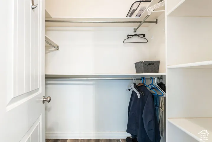 Reach-in closet featuring dual metal hanging rods, tiered white shelving, and a panel door