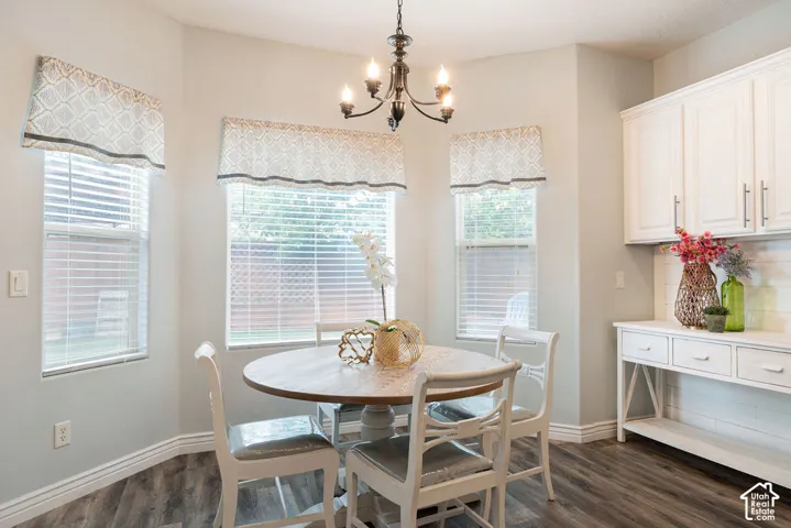 Bay window featuring three paneled windows, wood-finish flooring, white built-in cabinetry with horizontal shiplap backsplash, and a multi-arm metallic chandelier