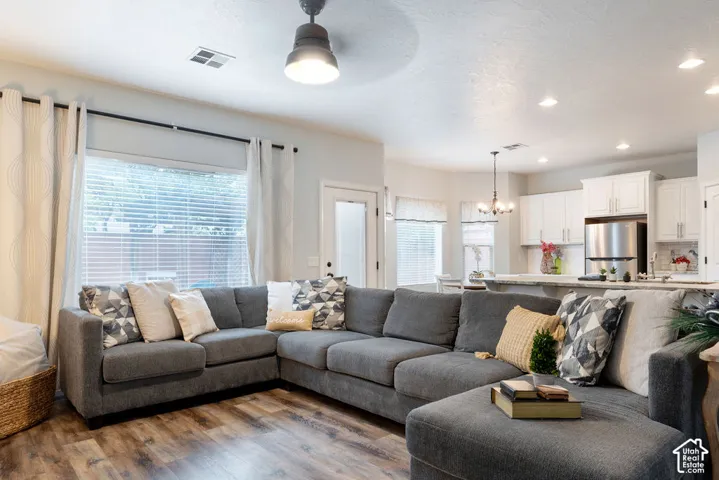 Open-concept interior featuring wood-finish flooring, recessed lighting, a modern ceiling fan, white shaker-style cabinetry, and stone-surface countertops