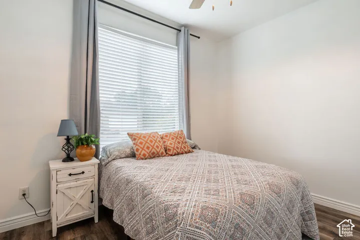 Wood-finish flooring, neutral wall tones, large window with horizontal blinds, and a ceiling fan