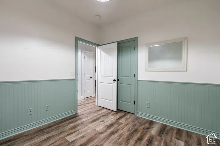 Room featuring beadboard wainscoting, wood-finish flooring, and multi-panel interior doors with matte black hardware