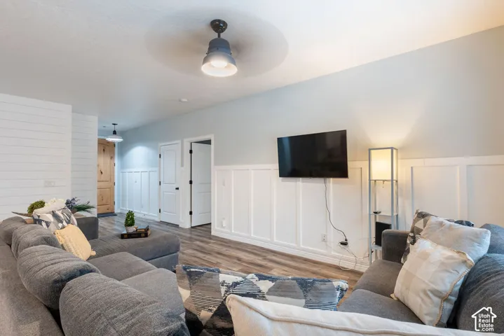 Interior space featuring white board-and-batten wainscoting, horizontal plank accent wall, wood-finish flooring, and industrial-style ceiling fan with integrated lighting