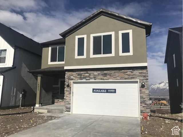 Two-story exterior featuring a stucco finish, stone veneer accents, an attached two-car garage, and a covered front porch