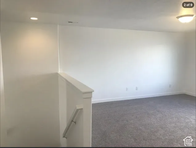 Neutral-toned wall-to-wall carpeting, recessed ceiling lighting, flush-mount fixture, and painted half-wall with a rail