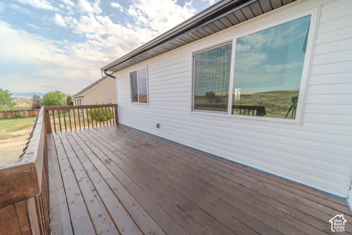 Elevated wood deck featuring a wooden railing, white horizontal siding, and large sliding windows