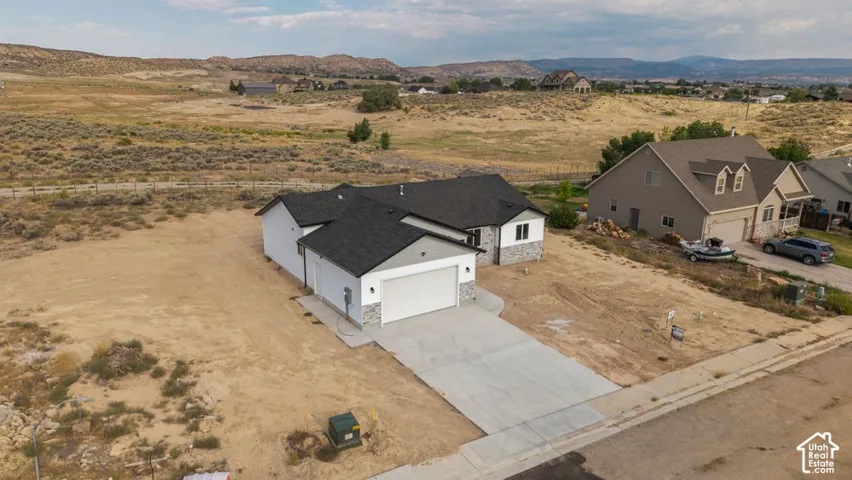 Single-level residence featuring a multi-gabled roofline, stone veneer siding accents, concrete driveway, and attached two-car garage