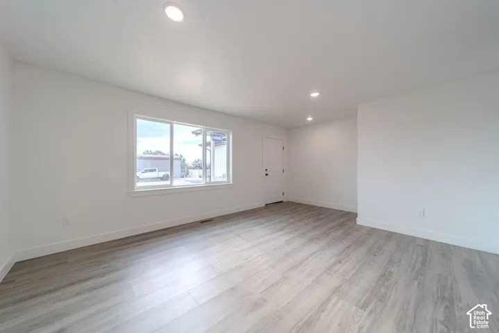 Open-concept room featuring neutral paint, wood-finish flooring, recessed lighting, and a multi-pane window