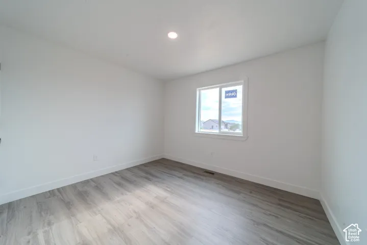 Neutral interior space featuring wood-finish flooring, crisp white walls, and a recessed ceiling light