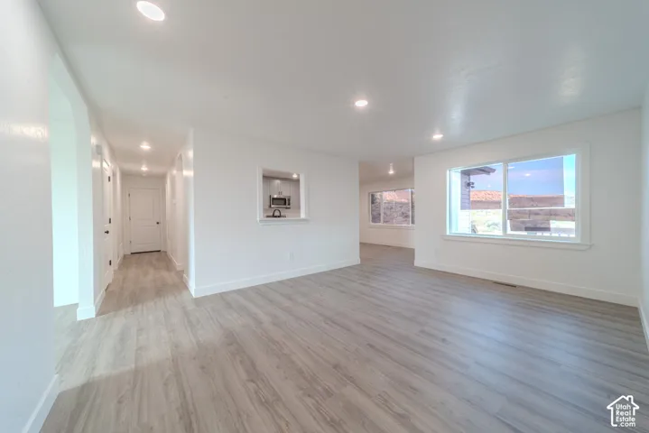 Neutral interior featuring wood-finish flooring, recessed lighting, and large windows with landscape scenery