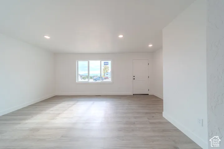 Neutral color palette featuring wood-finish flooring, recessed lighting, and a multi-pane window