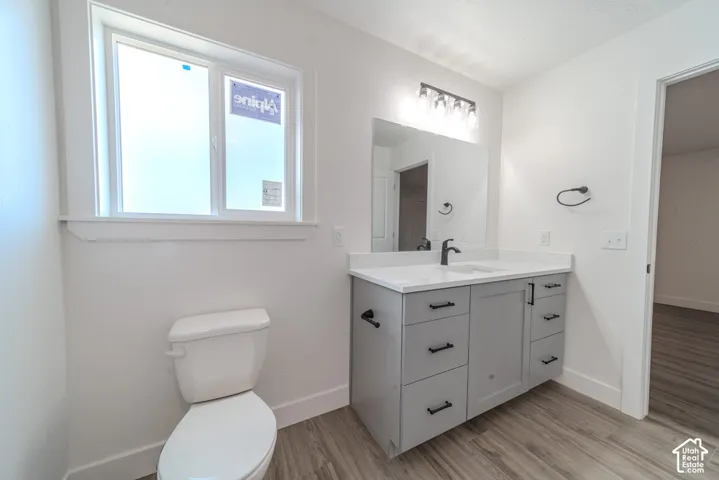 Grey cabinetry with matte black hardware, white countertop, rectangular undermount sink, matte black faucet, and wood-finish flooring