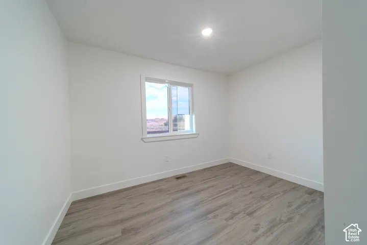 Neutral interior featuring wood-finish flooring, white walls, and a recessed ceiling light