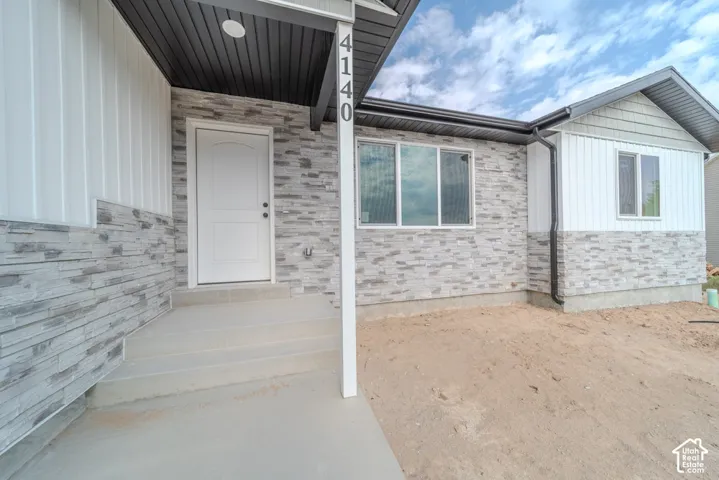 Exterior facade featuring horizontal stone veneer, vertical board-and-batten siding, shake-style gable accents, and a covered concrete entryway