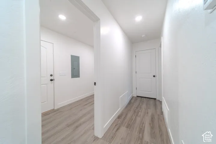 Hallway featuring wood-finish flooring, white panel doors, and recessed ceiling lighting