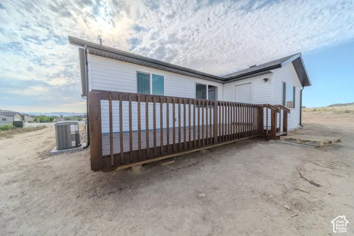 Exterior featuring horizontal siding, a raised wooden deck with a vertical-slat railing, and a mounted central air conditioning unit