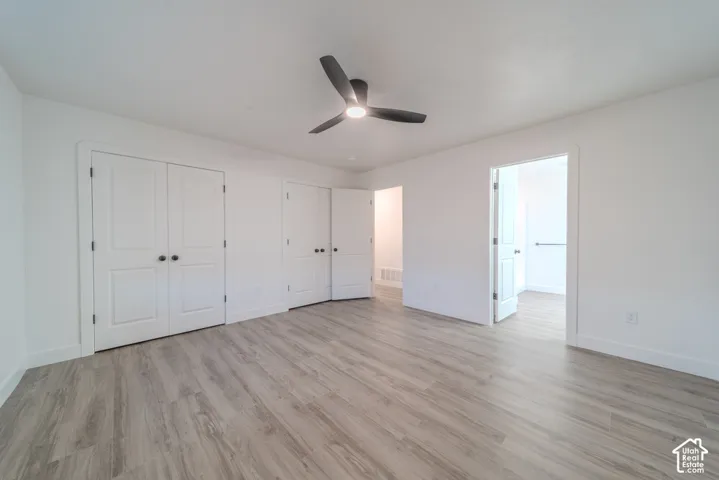 Room featuring wood-finish flooring, white panel doors, and a matte black ceiling fan with integrated lighting