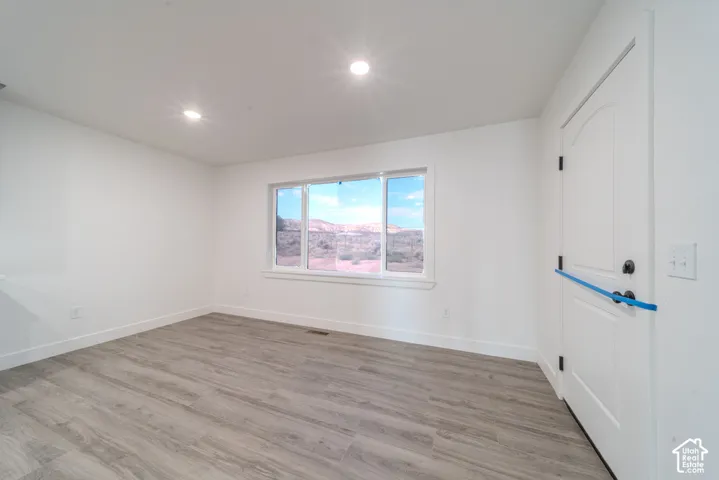 Room featuring neutral wall paint, wood-finish flooring, recessed lighting, and a large horizontal window with desert terrain backdrop