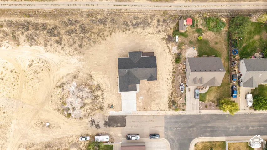 Aerial view of residential property featuring a multi-gabled asphalt shingle roof, a concrete driveway, and a spacious lot