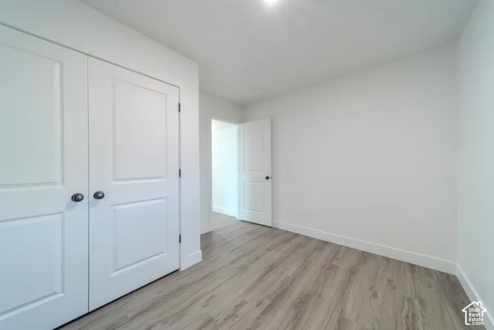 Room featuring wood-finish flooring, white walls, and two-panel interior doors with matte black hardware