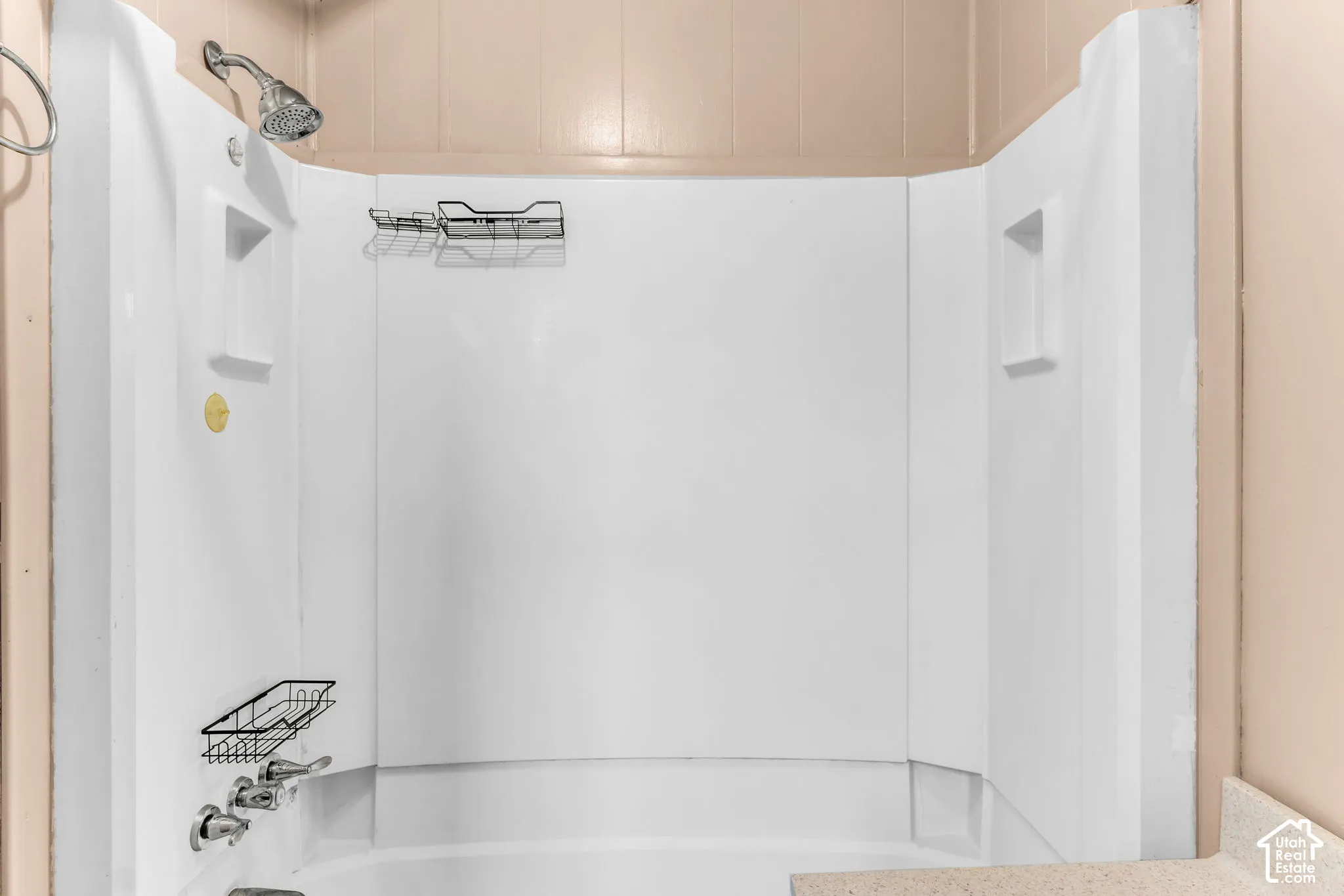 Shower enclosure featuring a white surround, integrated shelving niches, a chrome showerhead, and chrome handle fixtures