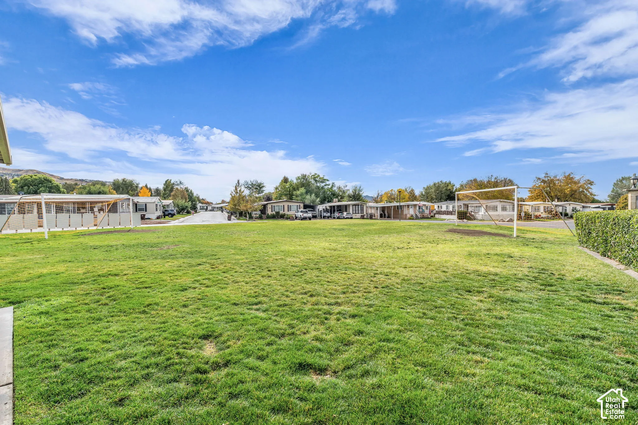 Expansive open green space featuring a maintained lawn, perimeter hedging, and metal athletic goal frames