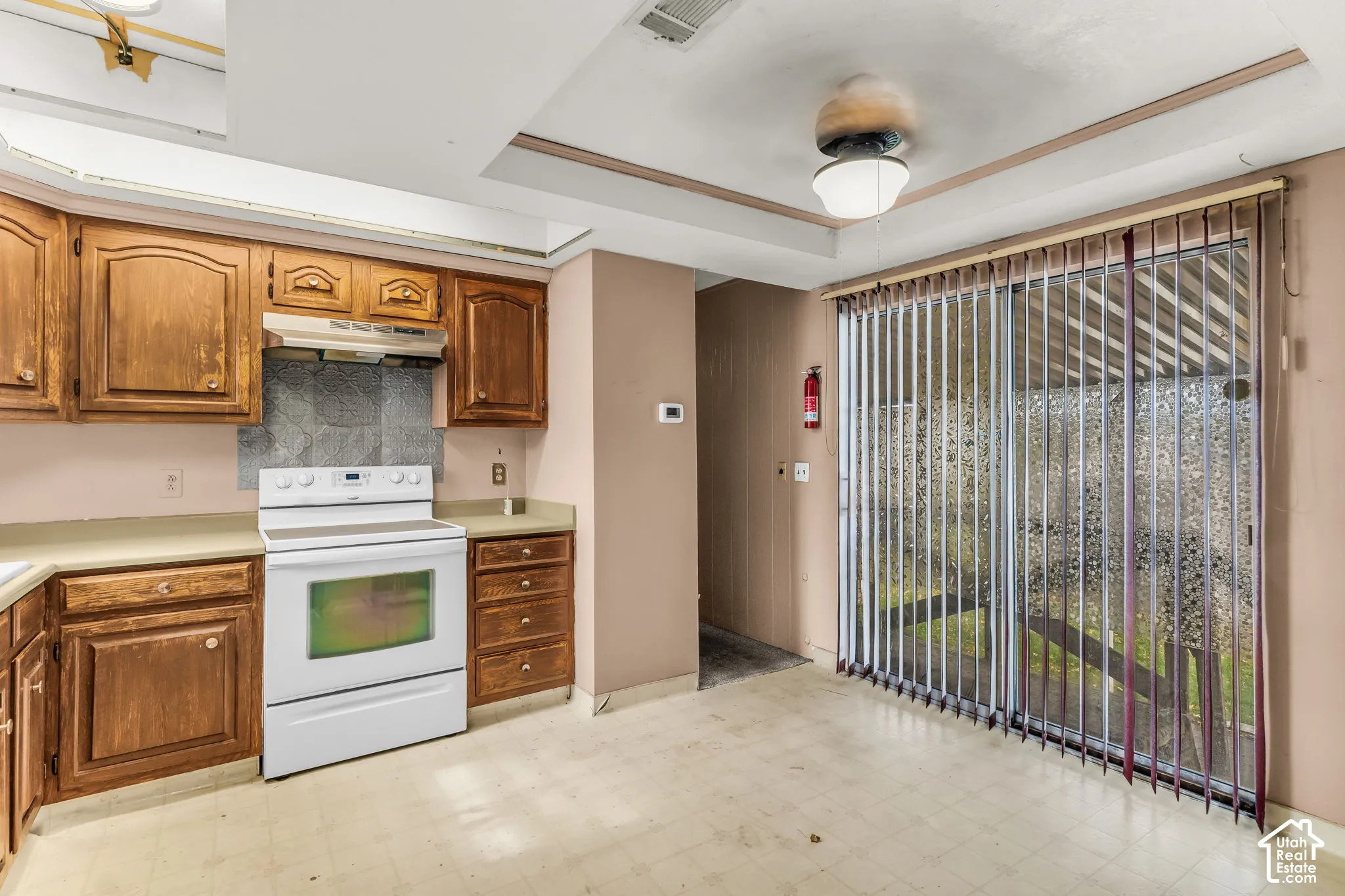Kitchen featuring wood cabinetry, solid-surface countertops, built-in range, tray ceiling, and sliding glass doors