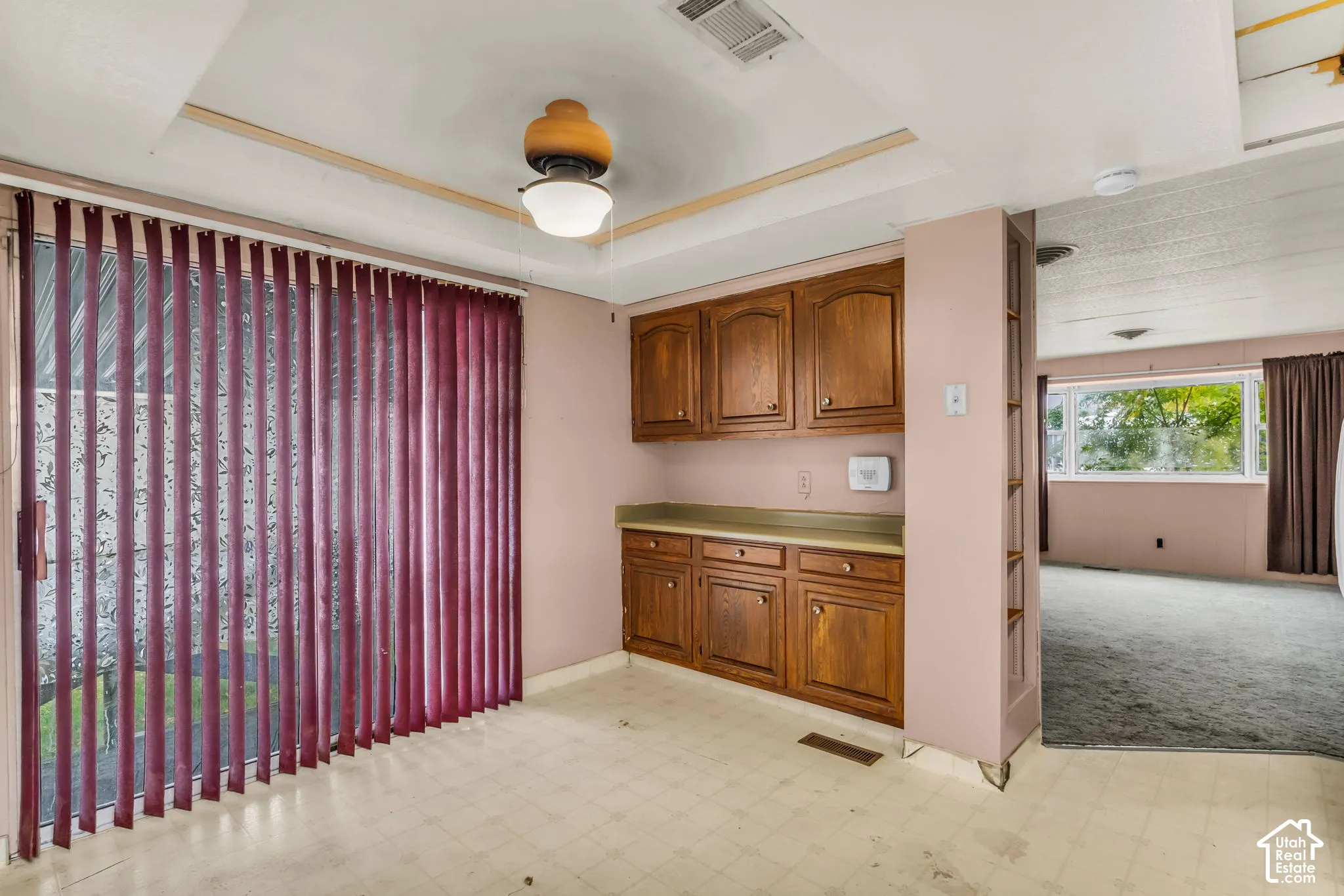 Built-in wood cabinetry with stone-surface countertop, sliding glass doors, recessed ceiling feature, and central light fixture with integrated ceiling fan