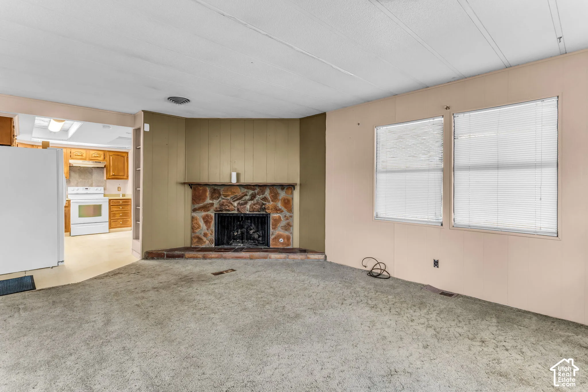 Corner fireplace featuring natural stone masonry, a built-in mantle, and multiple double-pane windows