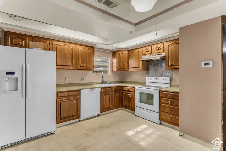 Kitchen featuring wood cabinetry, solid surface countertops, a tray ceiling, and a stainless steel vent hood
